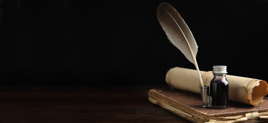 Quill, bottle of ink, old book and parchment scroll on wooden table, space for text. Banner design