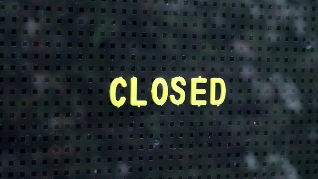 Close up of a man placing a closed sign in the window.