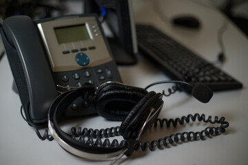 Stationary phone and headset on desk indoors, closeup. Communication support, call center and...