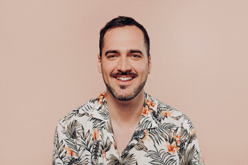 Young handsome cheerful man wearing hawaiian shirt over beige isolated background with a happy and cool smile on face. Lucky person. Summer concept.