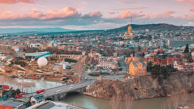 Tbilisi, Georgia. day to night time lapse timelapse. Top View Of Famous Landmarks In spring sunset Evening dusk night. Georgian Capital Skyline Cityscape. Justice House, Bridge Of Peace, Concert Hall