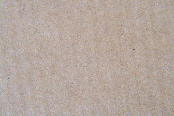 Close-up of recycled paper surface in selective focus. Brown paper background with hairs and debris.