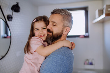 Happy father hugging his little daughter in bathroom.