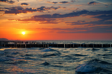 Wooden breakwater in the waters of the Baltic Sea. The sunset.
