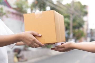 Postal service sending paper cardboard box to customer in front of a house outdoor. Shipping service arrival and send to customer address.