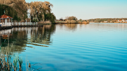 Fototapeta na wymiar blue lake during sunrise. wooden pier on the shore of the lake.