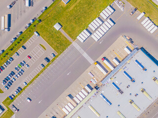 Aerial view of goods warehouse. Logistics center in industrial city zone from above. Aerial view of trucks loading at logistic center