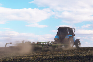 Tractor with planter cultivating field on sunny day. Agricultural industry