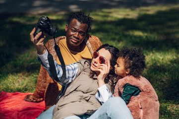 Beautiful multiracial family using a digital camera in the park.