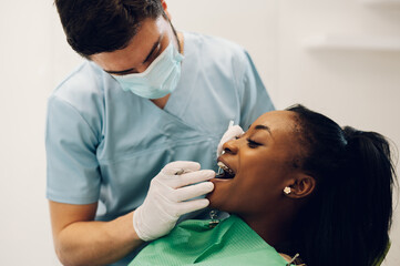 Obraz na płótnie Canvas Dentist providing dental care treatment to a african american female patient