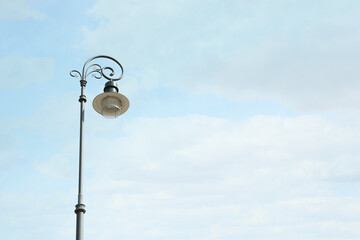 Old fashioned street light lamp against cloudy sky