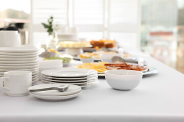 Clean dishware and different meals for breakfast on white table indoors. Buffet service