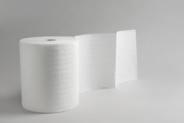 Roll of white paper towels on grey background. Space for text
