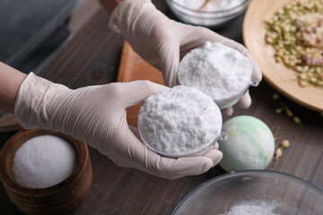 Woman in gloves making bath bomb at table, closeup