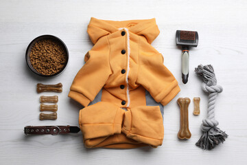 Flat lay composition with clothes, food and accessories for dog on white wooden table