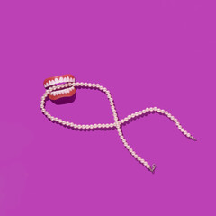 Creative layout with false teeth and white pearl necklace on bright pink background. 80s or 90s retro fashion aesthetic concept. Minimal romantic fashion idea.