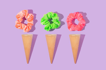 Summer creative layout with colorful scrunchies and ice cream cone on pastel purple background. 80s or 90s retro fashion aesthetic ice cream concept. Minimal  assesories idea.