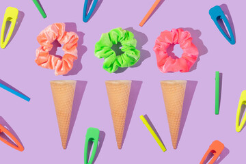 Summer creative layout with colorful scrunchies, hair pins and ice cream cone on pastel purple...