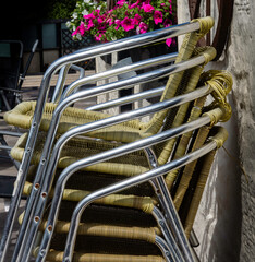 Stack of woven garden chairs with chrome frame