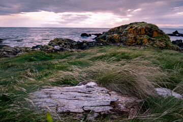 Rocky seascape beside Turnberry point lighthouse with cloudy moody sky  at coast line