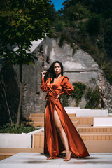 Sensual brunette beautiful woman luxury model posing in fluttering long dress outdoor