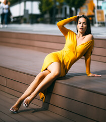 Sensual brunette beautiful woman luxury model posing in fluttering yellow color fashionable dress outdoor