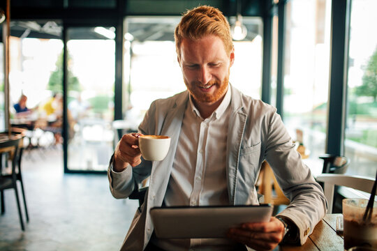Businessman working at tablet and drinking coffee during a break in cafe