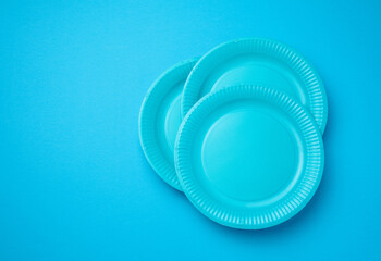 Empty white paper disposable plates on a bluen background, top view. The concept of rejection of plastic, environmental conservation