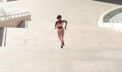 Fototapeta premium fitness, sport, exercise and lifestyle concept - a young African American woman running upstairs on the city stairs