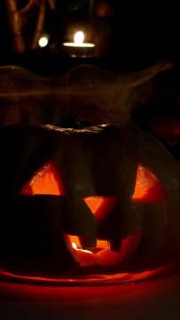 Home decoration with spooky glows halloween pumpkin head Jack Lantern face and burning candle.