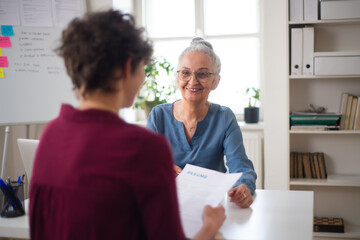 Fototapeta premium Senior woman recruiter smiling at young candidate during the job interview.