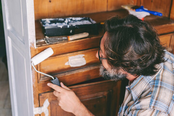 Mature man at home working on old renewed furniture. Concept of sustainability lifestyle and recycled circular market items. Happy male people in diy hobby leisure activity at home