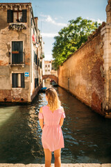 Fototapeta na wymiar Pretty girl in Venice. Woman standing on the bridge in Venice. Travel in Venice. Back view of pretty girl. Beautiful young woman visiting Europe.