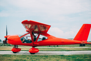 Red plane on the runway. Single turboprop aircraft parked on runway in sunny day. Travel sport concept. Ready for fly. small red propeller plane. 