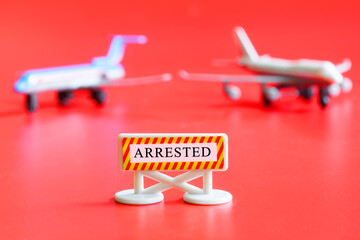 Sign with the inscription arrested and two toy airliners on a red background. The concept of the...