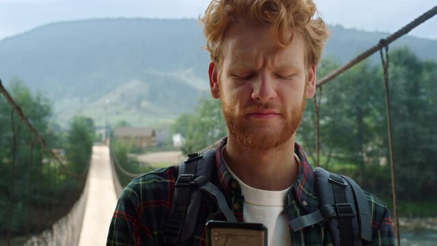 Sad traveler reading mobile phone screen. Hitchhiker looking map in mountains.