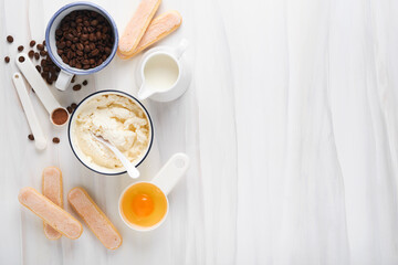 Tiramisu dessert. Ingredients for making dessert tiramisu. Cooking Italian food dessert Tiramisu with all necessary ingredients cocoa, coffee, mascarpone cheese on white stone background. Mock up.