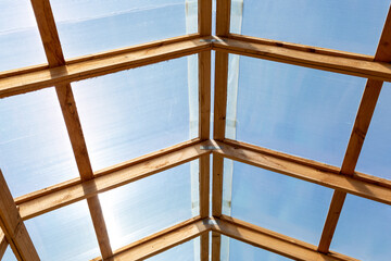 Roof of greenhouse, barn or other agricultural building is made of transparent polycarbonate and wooden boards