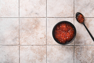 Red salmon caviar. Delicious red caviar in black bowl on old cracked tile table background. Top...