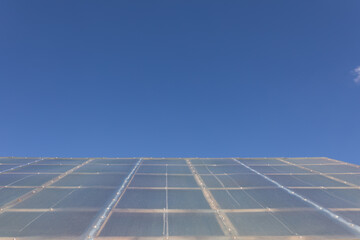 The pitched roof of a barn, outbuildings, a barn made of polycarbonate against a blue sky. Bottom...