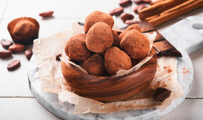 Chocolate truffles with cocoa powder in wooden dish on old cracked tile table background. Tasty sweet chocolate truffles candies. Valentine's Day and Mother's Day concept with copy space. Top view.