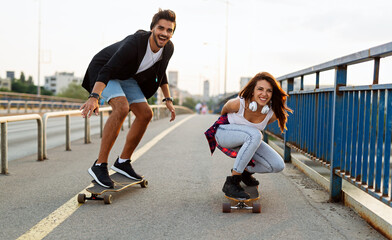 Portrait of happy couple having fun while driving a long board in city. People skateboard concept © NDABCREATIVITY
