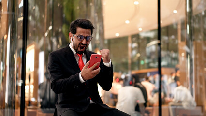 Young Businessman happy with Good News on Mobile phone