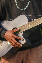 Midsection of man holding acoustic guitar
