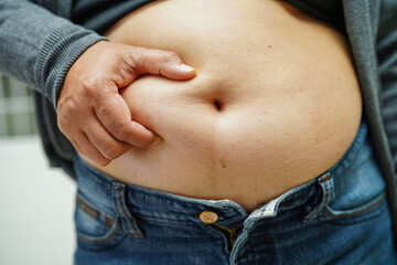 Naklejka premium Overweight asian woman use hand to squeeze fat belly big size overweight and obesity.