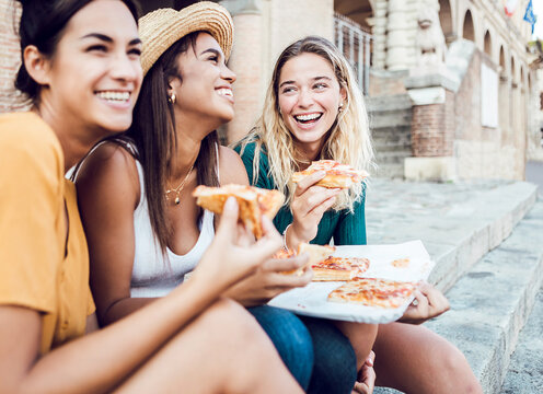 Fototapeta Happy young women eating italian pizza enjoying summer vacation - Three multiracial female teenager tourists having fun traveling together on holidays trip