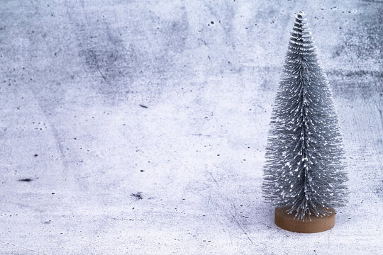 The photo shows a miniature Christmas tree on concrete background