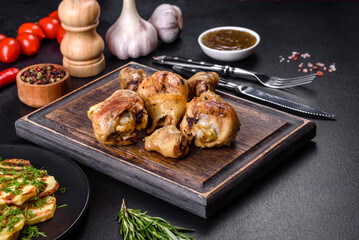 Three chicken legs grilled with spices and herbs on a wooden cutting board