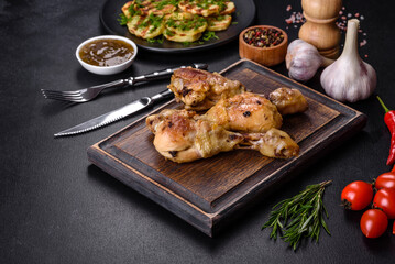 Three chicken legs grilled with spices and herbs on a wooden cutting board
