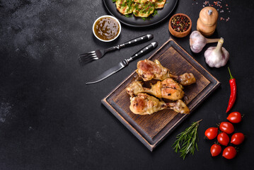 Three chicken legs grilled with spices and herbs on a wooden cutting board